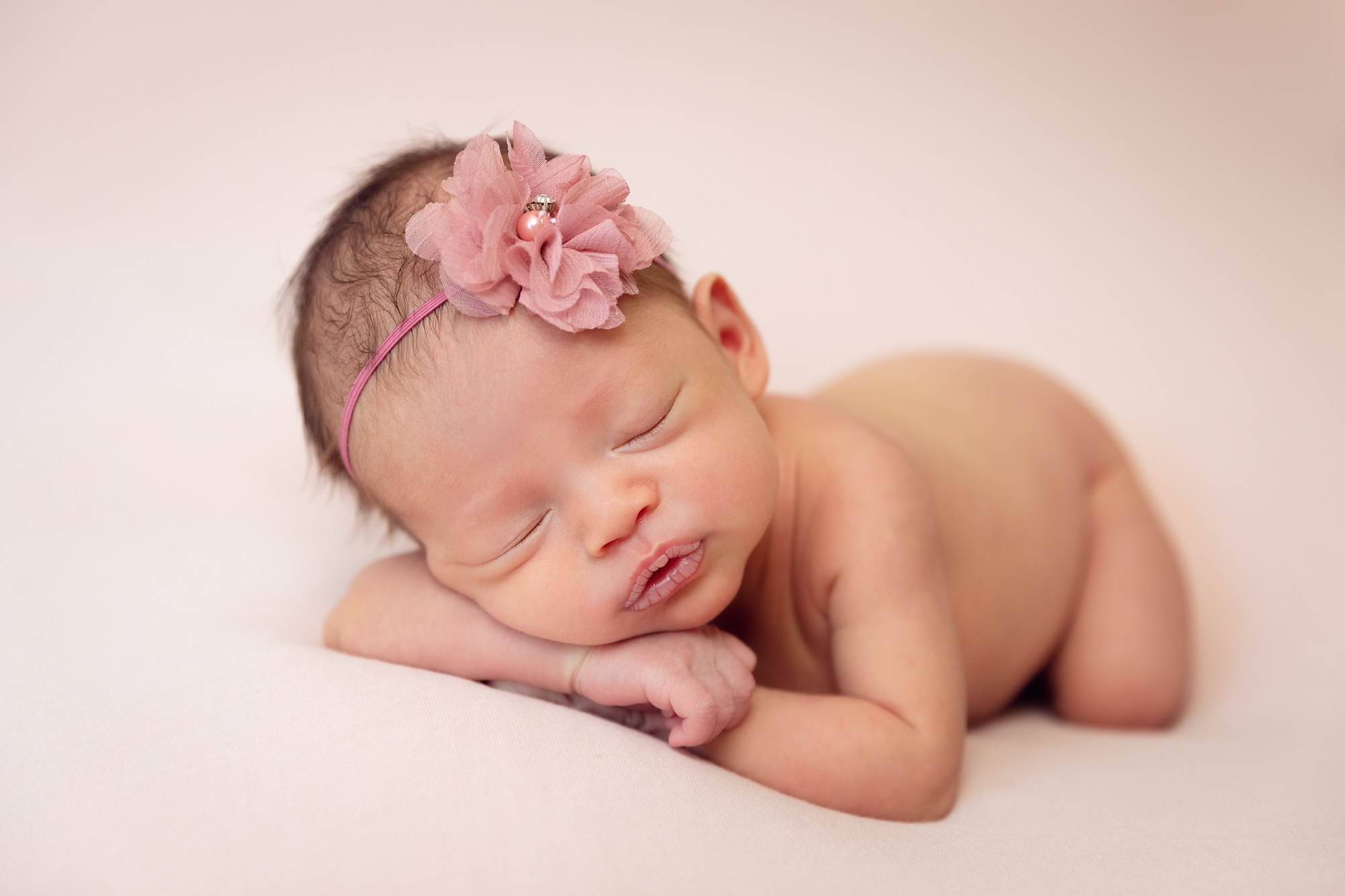 naked newborn baby girl on pink