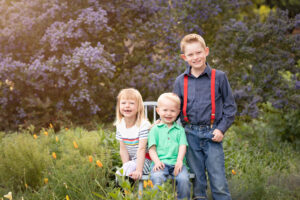 3 kids smiling in flower garden