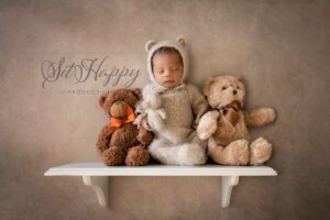 newborn baby boy in bear outfit on shelf