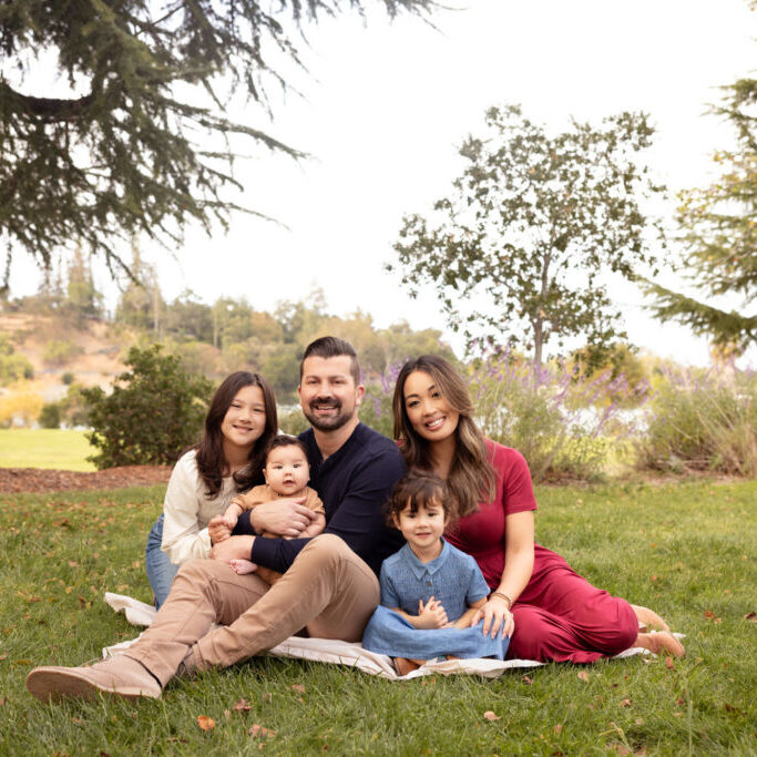 Family at Vasona Park on grassy hill with trees and folliage creating beautiful portrait of a family of five.